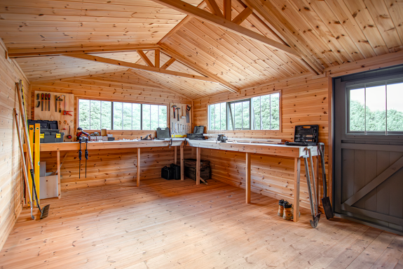 L-Shaped Workbenches inside a Superior Shed Spacious timber-lined garden workshop with exposed roof trusses, wraparound workbenches and organised tools.